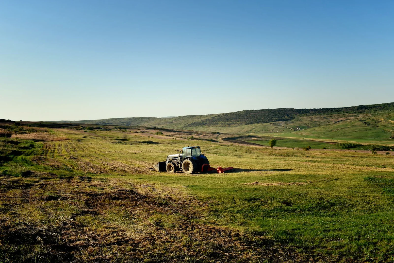 Trator a trabalhar numa paisagem agrícola, imagem ilustrativa